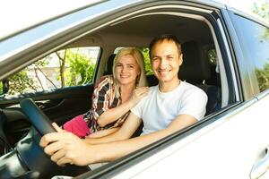 Happy young man and woman in a car enjoying a road trip on a summer day. photo