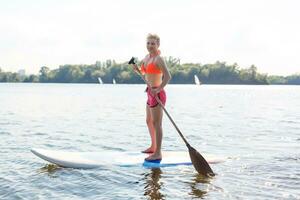 Young attractive woman on stand up paddle board in the lake, SUP photo