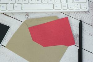 Red note inside brown envelope with keyboard on wooden desk. photo