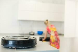 people, housework and technology concept - happy woman and robot vacuum cleaner photo