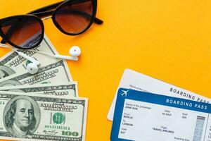 tourism, travel and objects concept - air ticket, money, over yellow concrete background photo