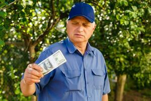 Cheerful senior holding money bundles in the garden background photo