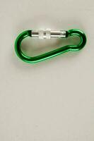 a green carabiner on a white surface photo