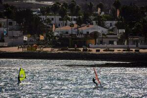 windsurfers in the ocean near a beach with houses photo