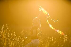 contento joven mujer corriendo con un cometa en un claro a puesta de sol en verano foto