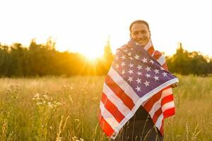 Fourth of July. Patriotic man with the national American flag in the field. Young man proudly waving an American flag. Independence Day. photo