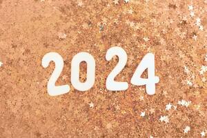 wooden number 2024 on christmas shiny Peach Fuzz background with sparkle festive golden confetti photo