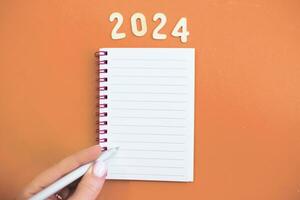 Top view of child hand with holding pen on white paper blank notebook and writing wish list. photo