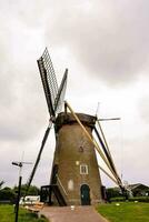 a windmill on a grassy field with a cloudy sky photo