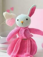 AI generated Knitted rabbit in pink dress. st. valentine's day decor. knitted toy, amigurumi. valentines day greeting card ai generated photo