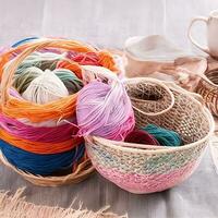 AI generated Multi-colored tangles of yarn in a wicker basket on the table. tea in a beautiful white cup. japanese style wabi sabi. home comfort, handicraft. ai generated photo