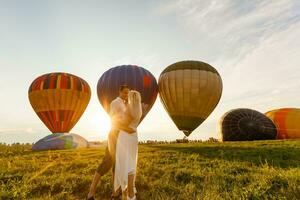 Beautiful romantic couple hugging at meadow. hot air balloon on a background photo