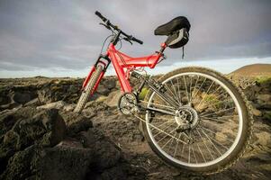 a red mountain bike is parked on a rocky hill photo