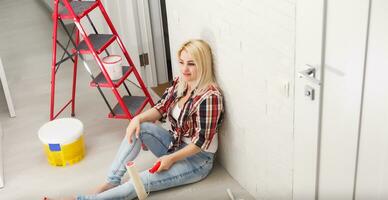 happy woman makes repairs in room at home photo