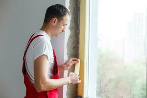 worker in uniform installs a plastic sandwich panel on the slopes of the window photo