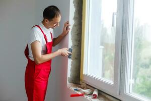 worker in uniform installs a plastic sandwich panel on the slopes of the window photo