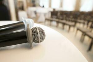 Table with microphones on the background of the room with rows of chairs. Press conference photo