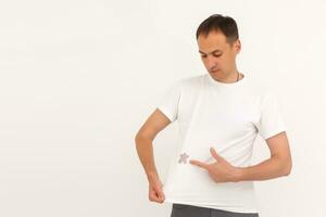 man shows a stain on his white t-shirt photo