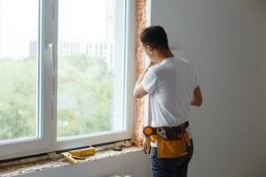 Man putting filling between window and wall in a new house photo