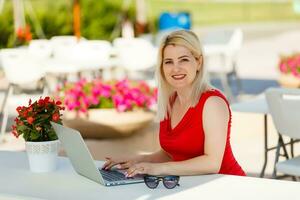 eufórico mujer buscando trabajo con un ordenador portátil en un urbano parque en verano foto
