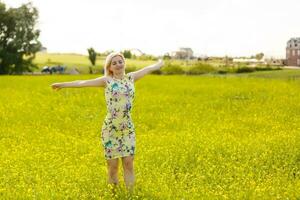 Young woman with her arms wide spread is enjoying in the sunny summer day, rear view photo