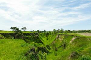 Spring photography, meadows, fields, ravines, hills, rural landscape. A deep, narrow gorge with steep slopes. A naturally raised area of land, not as high or craggy as a mountain. photo