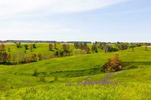 Spring photography, meadows, fields, ravines, hills, rural landscape. A deep, narrow gorge with steep slopes. A naturally raised area of land, not as high or craggy as a mountain. photo