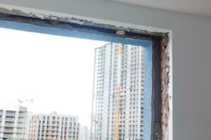 Empty frame on a wide panoramic window. Gorgeous view from the window of an apartment in a multi-storey building. Roofs of houses and trees from a height. Beautiful view through the window. Frame for photo