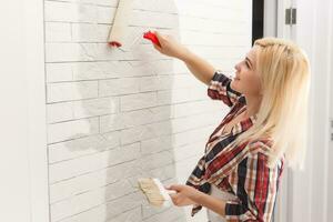 happy woman makes repairs in room at home photo