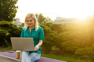 mujer buscando trabajo con un ordenador portátil en un urbano parque en verano foto