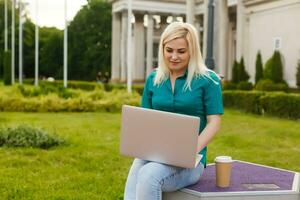 mujer buscando trabajo con un ordenador portátil en un urbano parque en verano foto