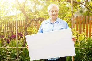 elderly woman holding a blank vertical canvas in her hands. Empty frame for text or photo. woman with mockup poster photo