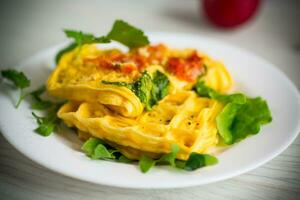 Egg omelet stuffed with tomato and greens fried in the form of waffles photo