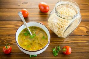 Chicken noodle soup with parsley and vegetables in a white plate photo