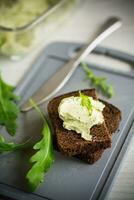 bread cheese spread with garlic and arugula on dark bread photo