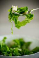 Fresco verde lechuga ensalada con queso Mozzarella y hierbas en un tenedor foto