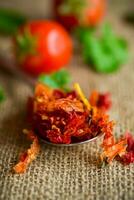 small pieces of dried tomatoes next to fresh tomatoes photo