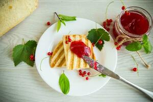 fried bread croutons for breakfast with redcurrant jam in a plate with berries photo