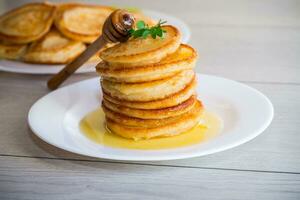 cooked sweet pancakes with honey in a plate photo