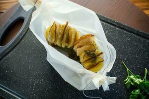 Baked potatoes stuffed with lard in baking paper. photo