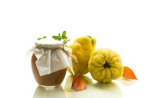 Ripe quince fruit with jam in a glass jar isolated on a white background. photo