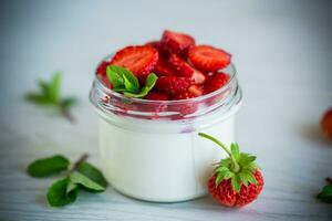 Sweet homemade yogurt with fresh ripe strawberries in a glass jar photo