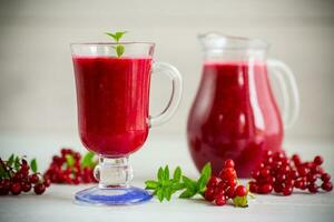 recién exprimido grueso natural jugo con pulpa desde maduro rojo viburnum en un licorera foto