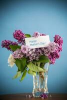 bouquet of different blooming spring lilacs in a vase on blue background photo