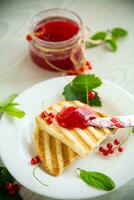 fried bread croutons for breakfast with redcurrant jam in a plate with berries photo