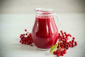 recién exprimido grueso natural jugo con pulpa desde maduro rojo viburnum en un licorera foto