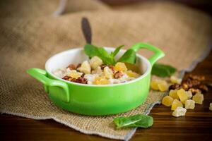 cooked boiled sweet oatmeal with nuts and candied fruits in a bowl photo