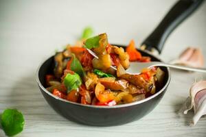 fried eggplants with peppers, tomatoes, onions and garlic photo