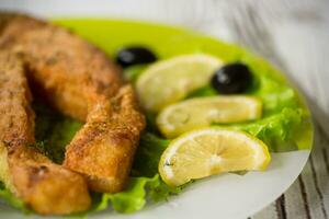 piece of fried salmon fish in a plate with lemon photo