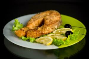 piece of fried salmon fish in a plate with lemon photo